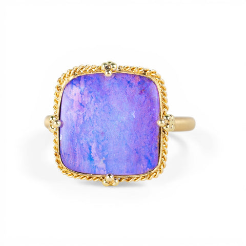 Gold ring with a purple boulder opal stone on a white background