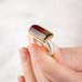 Close up of hand holding a watermelon tourmaline ring with gold bezel and silver band
