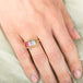 Gold ring with a watermelon tourmaline gemstone on a hand against a neutral background