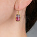 Gold earring with a tourmaline gemstone worn by a person