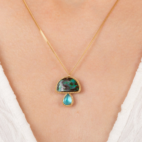 Gold necklace with a mushroom pendant featuring boulder opal and aquamarine stones on a person