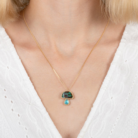 Gold necklace with a mushroom pendant featuring boulder opal and aquamarine stones on a person