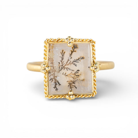 Gold ring with a dendritic quartz stone featuring natural inclusions on a white background