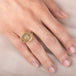 Gold ring with a dendritic quartz stone and intricate design on a hand