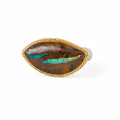 Ring with an opalized wood stone, gold setting and silver band on a white background