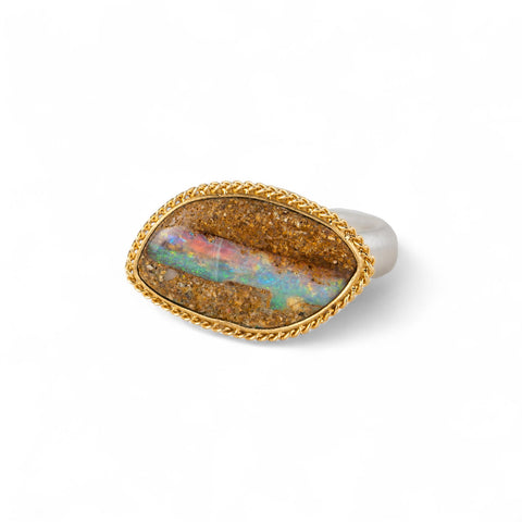 Ring with an opal stone, gold setting and silver band on a white background