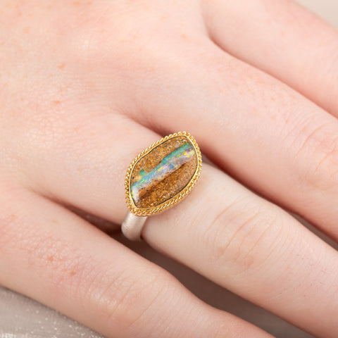Ring with an opal stone, gold setting and silver band on a hand