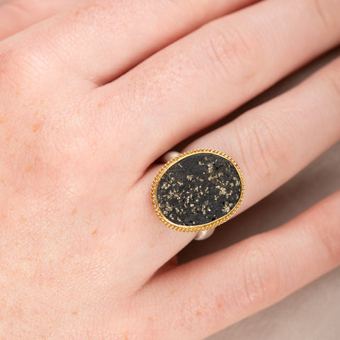 Gold and silver ring with slate with pyrite stone on a hand