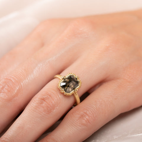 A close up of a model wearing an 18k yellow gold and black diamond ring.