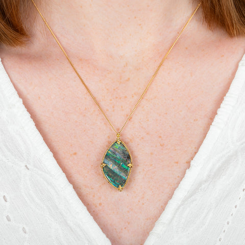 A model wears a boulder opal and 18k yellow gold necklace.