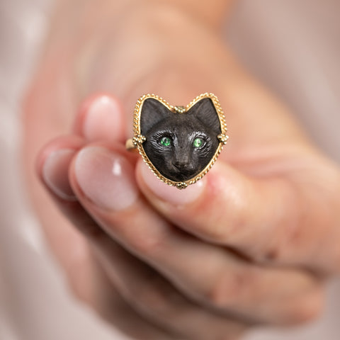 Close up of a model holding an 18k yellow gold and onyx cat ring.