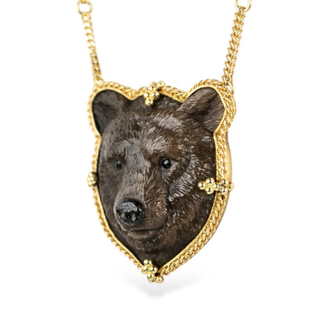 A hand-carved jasper gemstone in the shape of a grizzly bear and set in 18k yellow gold.