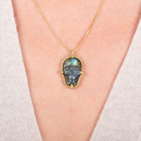 Carved labradorite skull necklace on a model