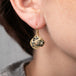 A model wears a leopard jasper earring featuring a leopard carving set in 18k gold.