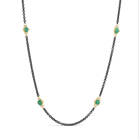 A necklace with oxidized sterling silver chains featuring woven 18k gold strands with Emeralds, displayed on a white background.