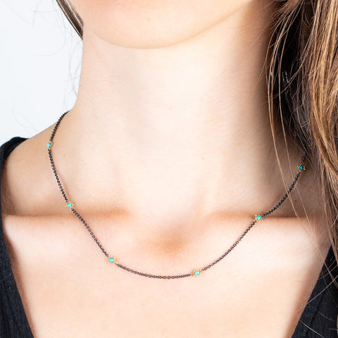 A model wears an oxidized silver and 18k yellow gold chain necklace with turquoise gemstone beads.