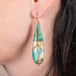 Draped petrified wood blue opal earrings on a model