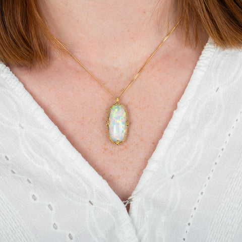 A model wearing an oval ethiopian opal and 18k yellow gold necklace.