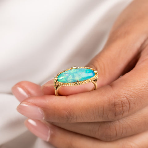A model wears an ethiopian opal and 18k yellow gold ring.