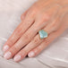 A model wears an 18k yellow gold and aquamarine ring that has facets and inclusions.