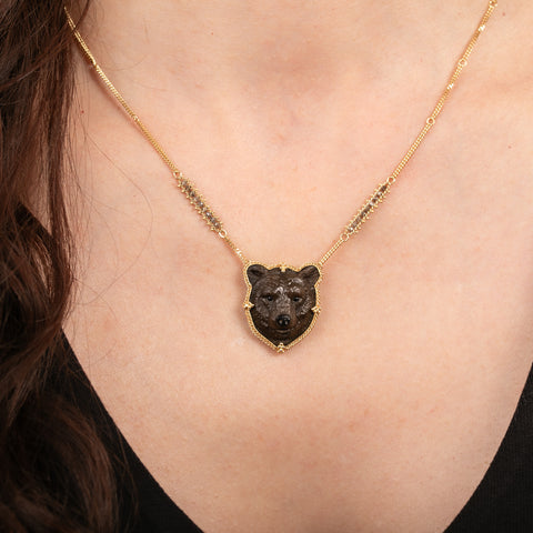 A model wearing a carved grizzly bear gemstone and 18k gold necklace.