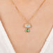 Gold necklace with a mushroom pendant featuring opal and emerald stones on a person