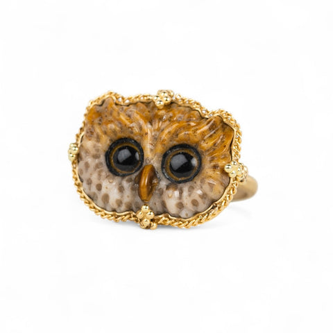 18k yellow gold ring featuring an owl face carved from leopard jasper with two large round eyes and a small orange beak.