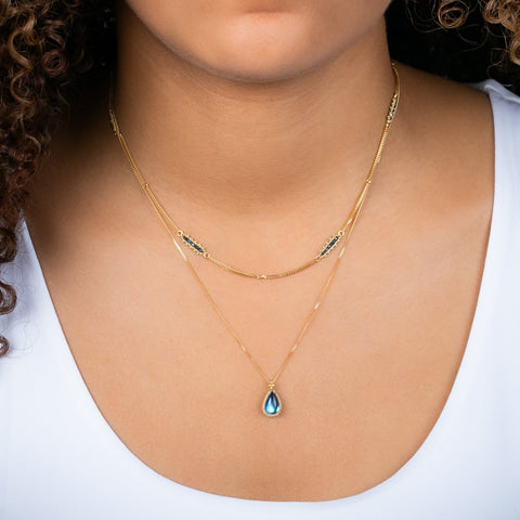 A teardrop-shaped moonstone pendant set in an 18k yellow gold bezel, suspended from a matching gold chain.