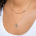 A model wears a teardrop-shaped moonstone pendant set in an 18k yellow gold bezel, suspended from a matching gold chain.