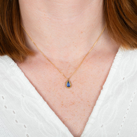 A model wears a tanzanite teardrop and 18k gold necklace.