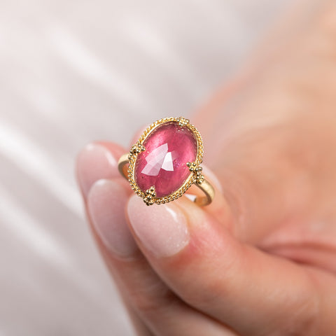A model holds an 18k yellow gold and pink tourmaline oval ring.