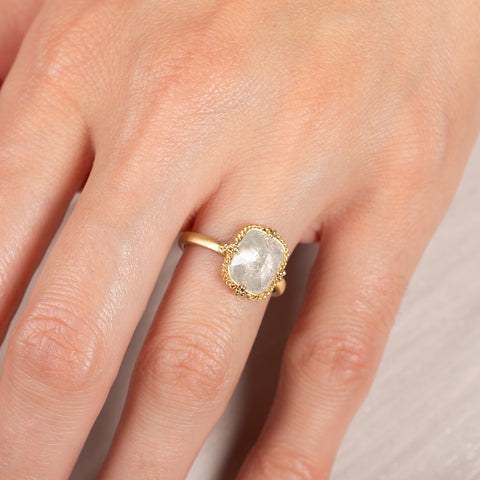 A close up of a model wearing an 18k yellow gold and silver diamond ring.