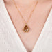 A close up of a model wearing a teardrop shaped Spessartite and 18k gold necklace.