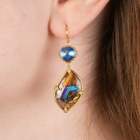A model wears handmade 18k yellow gold drop earrings featuring Yowah nut opals and moonstones.