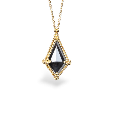 A Kite-shaped Black Diamond pendant is set in an 18k yellow gold bezel, suspended from an 18K yellow gold chain. Diamond exhibits fierce boldness and captivating facets that dance in the light. Set in a distinctive one-of-a-kind design with handmade gold bezel, braided detail, and granulation.