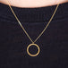 A close up of an 18k yellow gold circular pendant crafted in chain to create a stardust-like effect