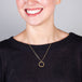 A model wears a delicate 18k yellow gold chain necklace with a small circle pendant crafted in chain to create a stardust-like effect