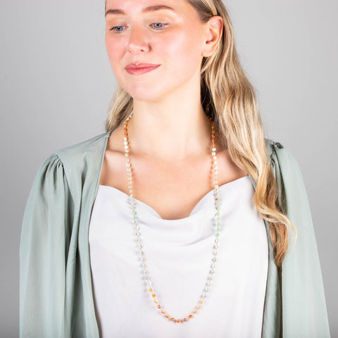 A model wears a long mixed-opal bead necklace featuring shades of burnt orange, teal and periwinkle woven with 18k yellow gold chain.