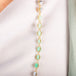 A close up of a mixed opal bead necklace featuring teal stones that are woven with 18k yellow gold chain. 