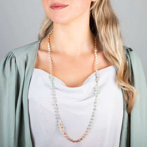 A model wears a long mixed-opal bead necklace featuring shades of burnt orange, teal and periwinkle woven with 18k yellow gold chain.