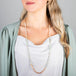 A model wears a long mixed-opal bead necklace featuring shades of burnt orange, teal and periwinkle woven with 18k yellow gold chain.