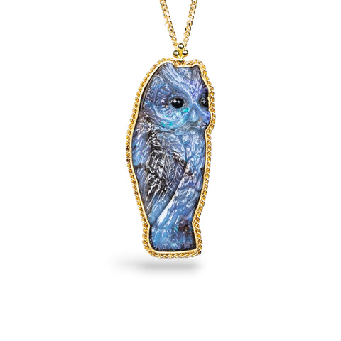 Boulder Opal owl pendant in 18K yellow gold, meticulously carved with intricate details in feathers, eyes, and beak. Set in a handmade gold bezel with braided detail, suspended from an 18K yellow gold chain.