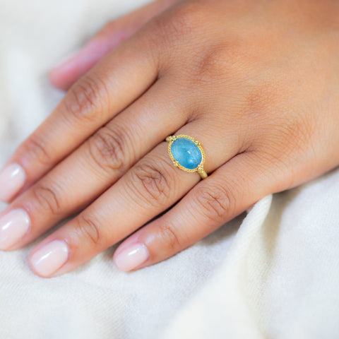 An intricate Aquamarine ring in 18K yellow gold, capturing the enigmatic depths of a deep blue sea. Handmade gold frame with braided gold accents and granulated prongs. Handmade in New York