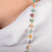 A close up of a multi-colored gemstone necklace set in 18k yellow gold. The stones include Aquamarine, Opal, apatite, Moonstone, Tanzanite, Carnelian, Tourmaline, Amazonite, Rhodochrosite, Chalcedony, and Jade.