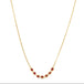 This delicate 18k yellow gold necklace features a row of seven woven ruby beads in the center. The necklace is finished with a lobster clasp closure