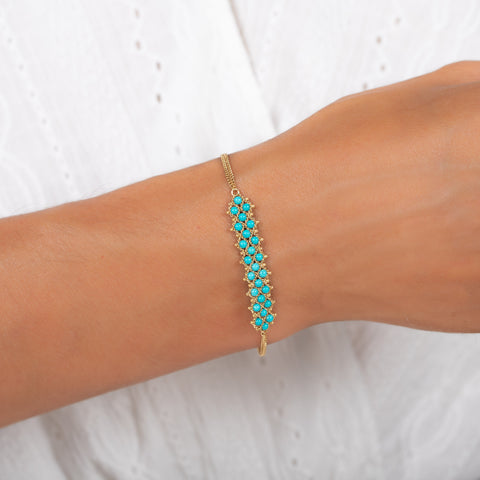 A model wears a delicate 18k yellow gold chain bracelet featuring three rows of woven turquoise beads in the center. The bracelet is finished with a lobster clasp closure.