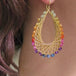 A video of a model wearing earrings made of 18k yellow gold chain and a rainbow of tiny gemstones.