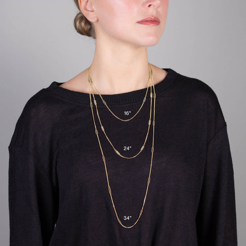 A model wears three 18k yellow gold chain necklaces with silver diamond stations placed throughout. The chains vary in length from 16" to 24" to 34".