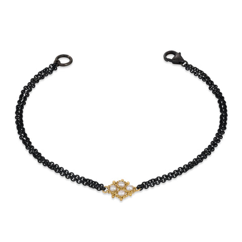 This delicate bracelet features double oxidized sterling silver chains with an 18k yellow gold and white pearl lattice in the center.