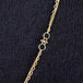 A close-up of a delicate woven 18k yellow gold chain necklace with a black diamond bead station.